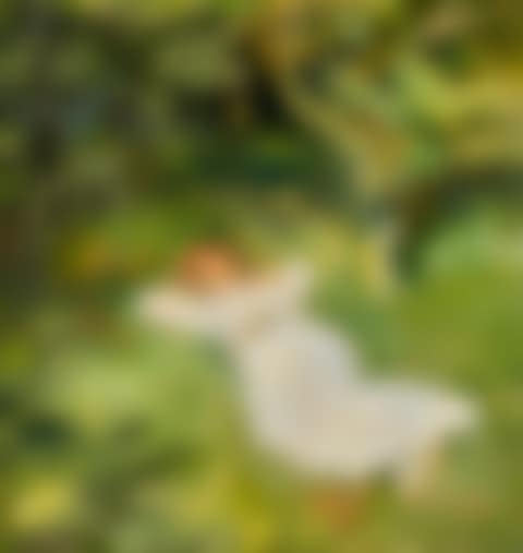 A young woman in a white dress lying under a tree in the garden (preview)