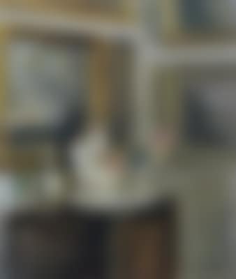 Interior from a corner of a living room with paintings on the walls and a vase, dish, and flowers on the chest of drawers (preview)