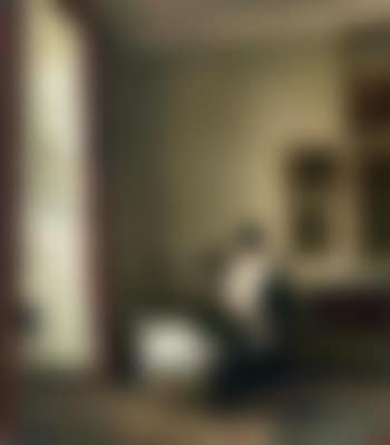 Interior from a corner of the living room with a mother breastfeeding her child. In the window niche a large monstera plant. On the back wall several paintings and a chest of drawers with a silver plate, a small sculpture and a bonbonnière (preview)