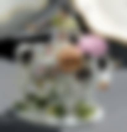 Statuette representing a young woman dressed in a dress with Indian flowers, holding a basket, sitting on a cow, on an oval terrace decorated with flowers in relief (preview)